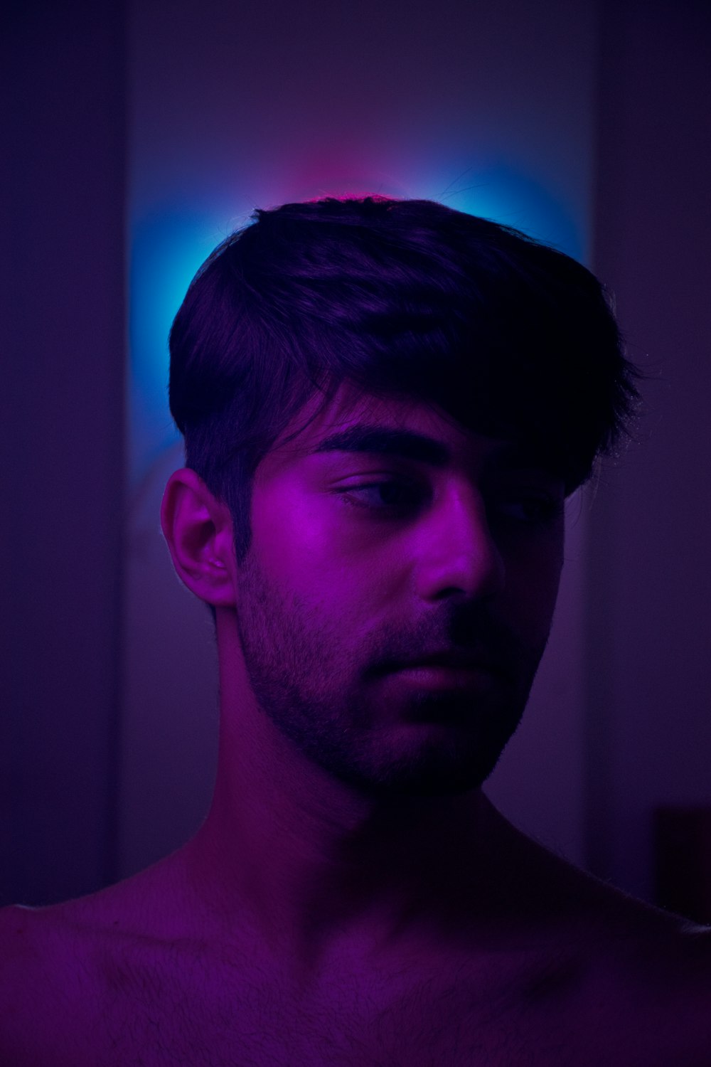 a man in a dark room with a purple light