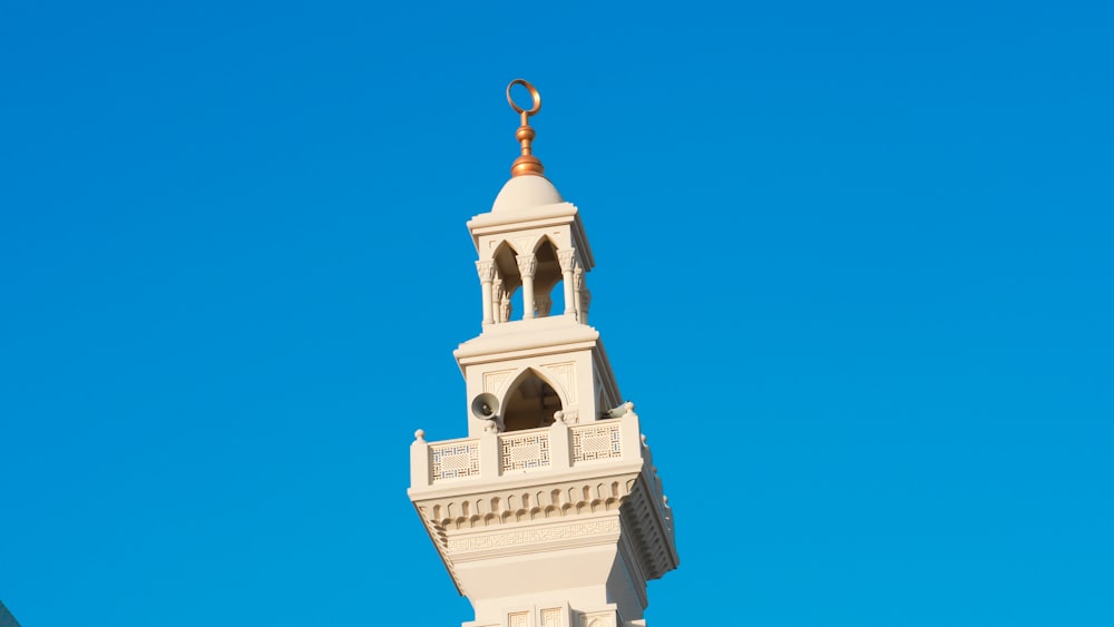 a tall white clock tower with a gold top