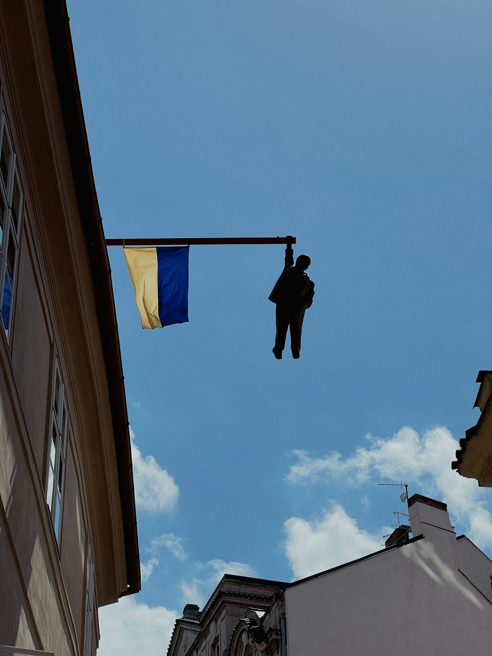 a person hanging from a street light with a building in the background