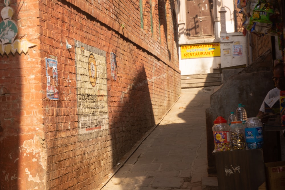 a narrow alleyway with a brick wall and graffiti on it