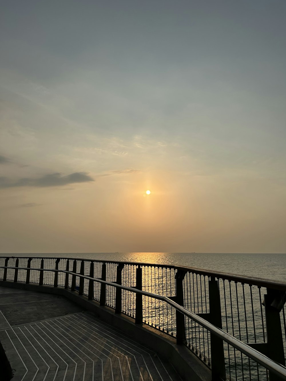 the sun is setting over the water from a pier