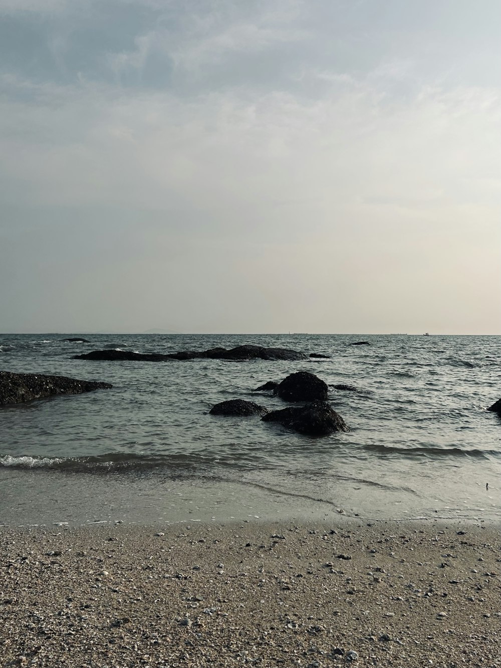 a beach with rocks and water under a cloudy sky