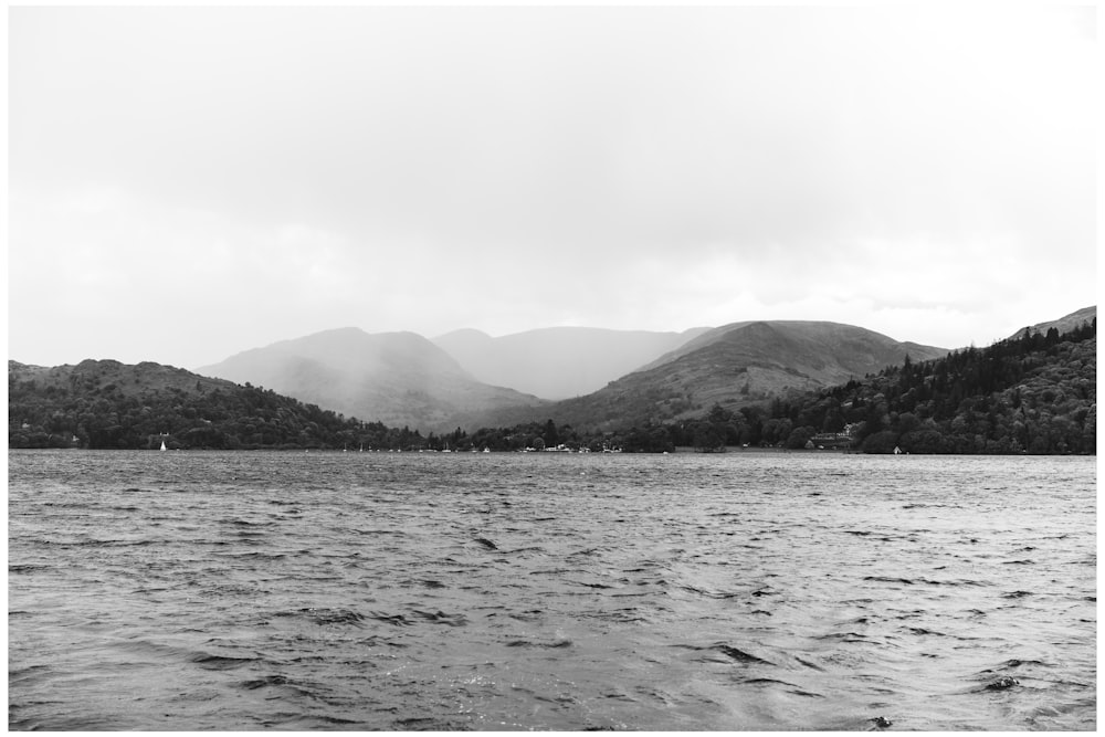 背景に山がある湖の白黒写真