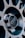 Close-up view of a car wheel rim with a focus on the center cap, which has a carbon fiber pattern and a logo imprinted on it. The design is intricate, with metallic spokes radiating from the center.