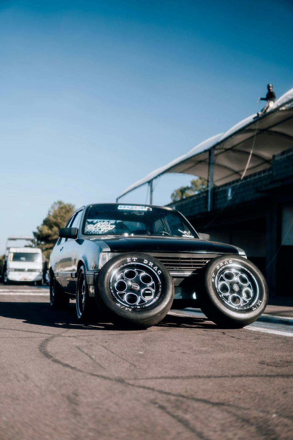 a black car with chrome wheels parked on the side of the road