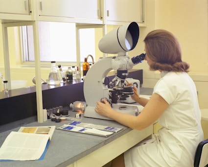 a woman looking through a microscope in a laboratory