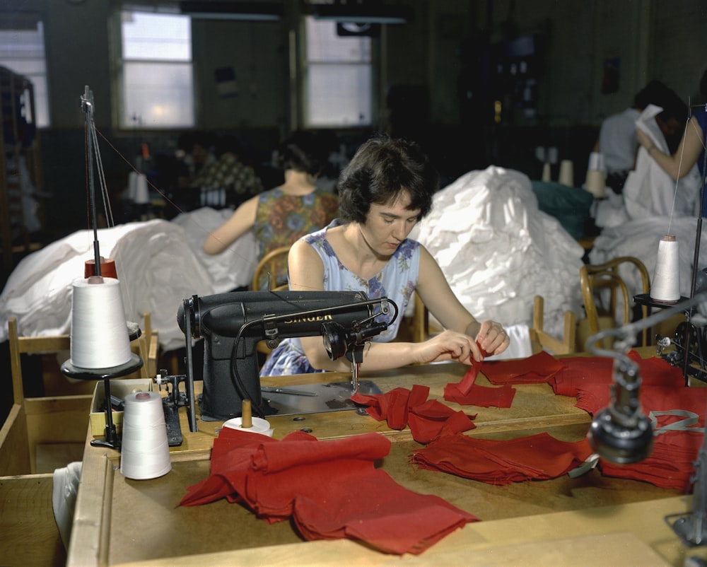 a woman sitting at a table with a sewing machine