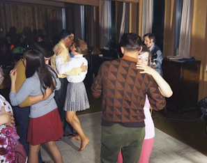 Couples dancing closely at a jazz night event in a dimly lit venue with a live band.
