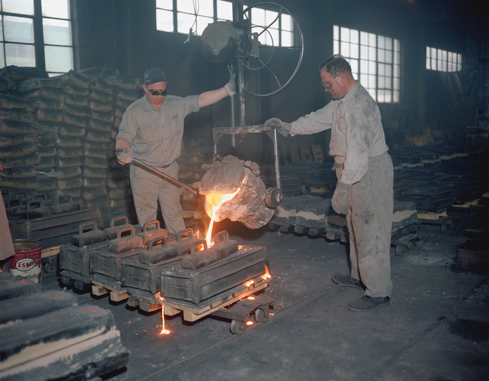 Due uomini in una fabbrica che lavorano su un pezzo di metallo