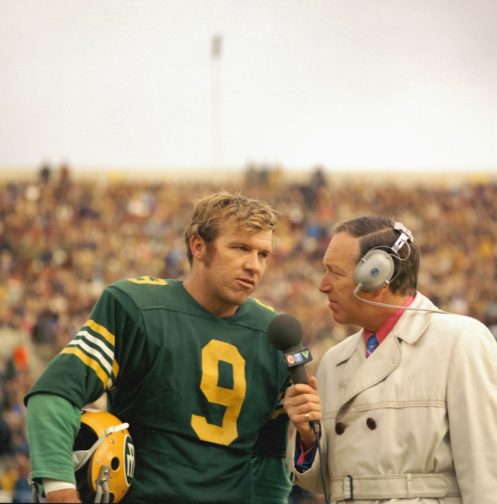 a football player talking to an announcer on the sidelines