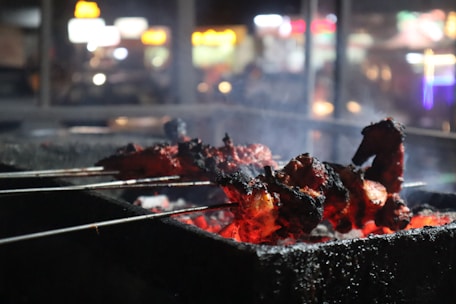Close-up of juicy Burdur şiş skewers grilling over hot coals with smoke rising.