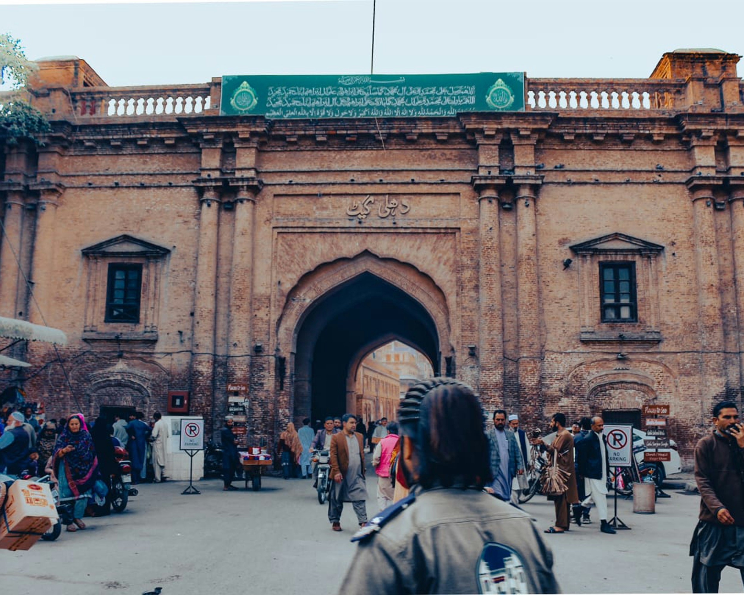 A group of Hindu women devotees, clearly tired from walking, are seen accepting water from a Muslim man standing outside a mosque, with a welcoming smile.