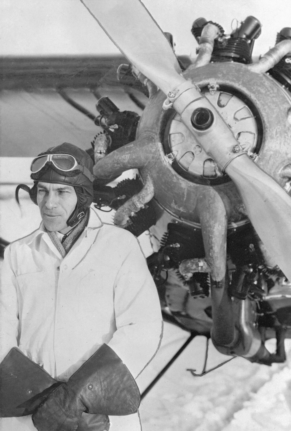 a black and white photo of a man standing in front of an airplane