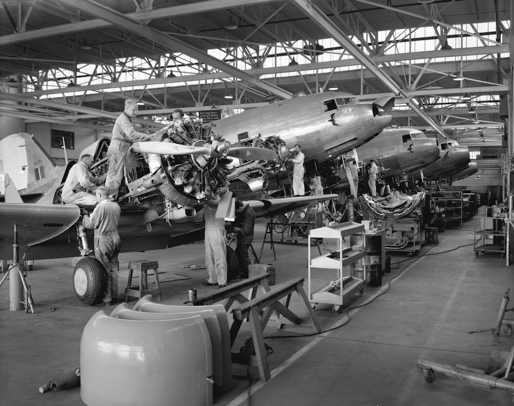 a black and white photo of men working on an airplane