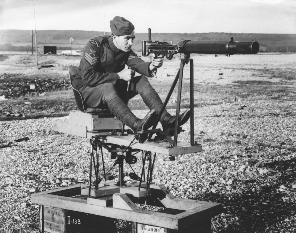 um homem sentado em cima de uma metralhadora