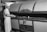 A baker dressed in white uniform and cap uses a long-handled peel to place or retrieve bread from a large industrial oven labeled 'Master Baker Oven'. The setting appears to be a bakery or a baking manufacturing facility.