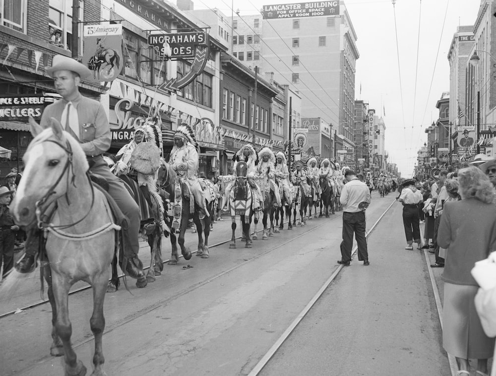 a group of people riding horses down a street