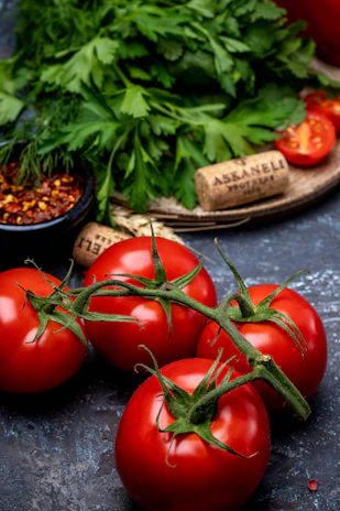 Close-up of ripe tomatoes and fresh herbs laid out on a rustic wooden surface, highlighting natural textures.