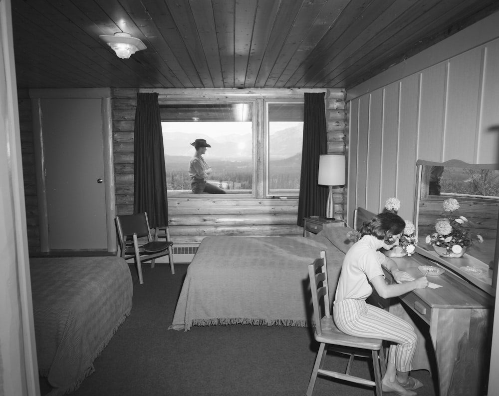 a black and white photo of a woman sitting at a desk