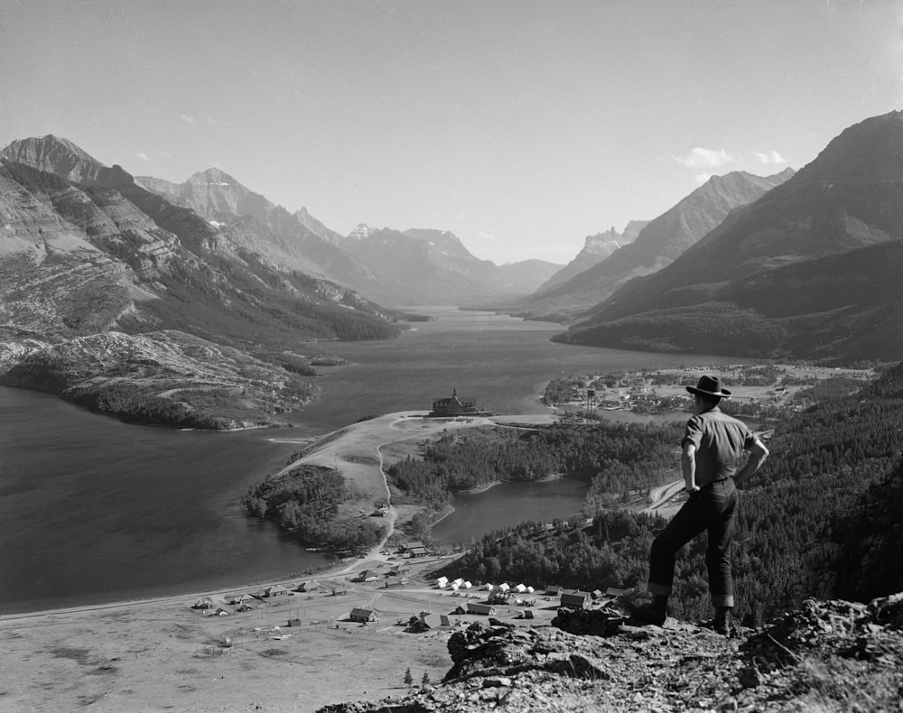 a man standing on top of a mountain next to a lake