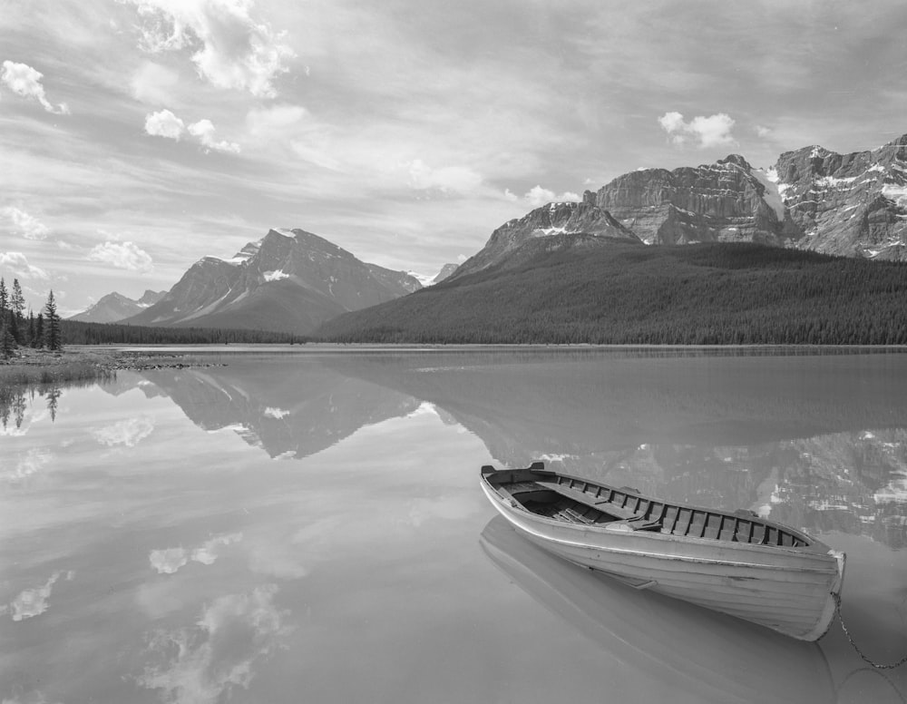 a boat sitting on top of a lake surrounded by mountains