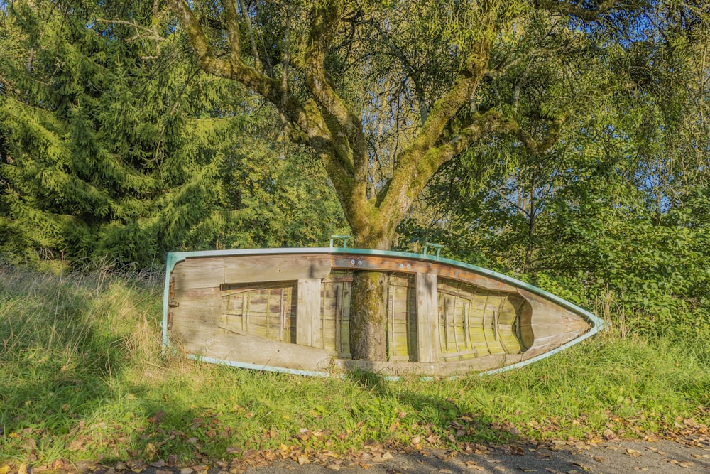 a wooden boat sitting on top of a lush green field