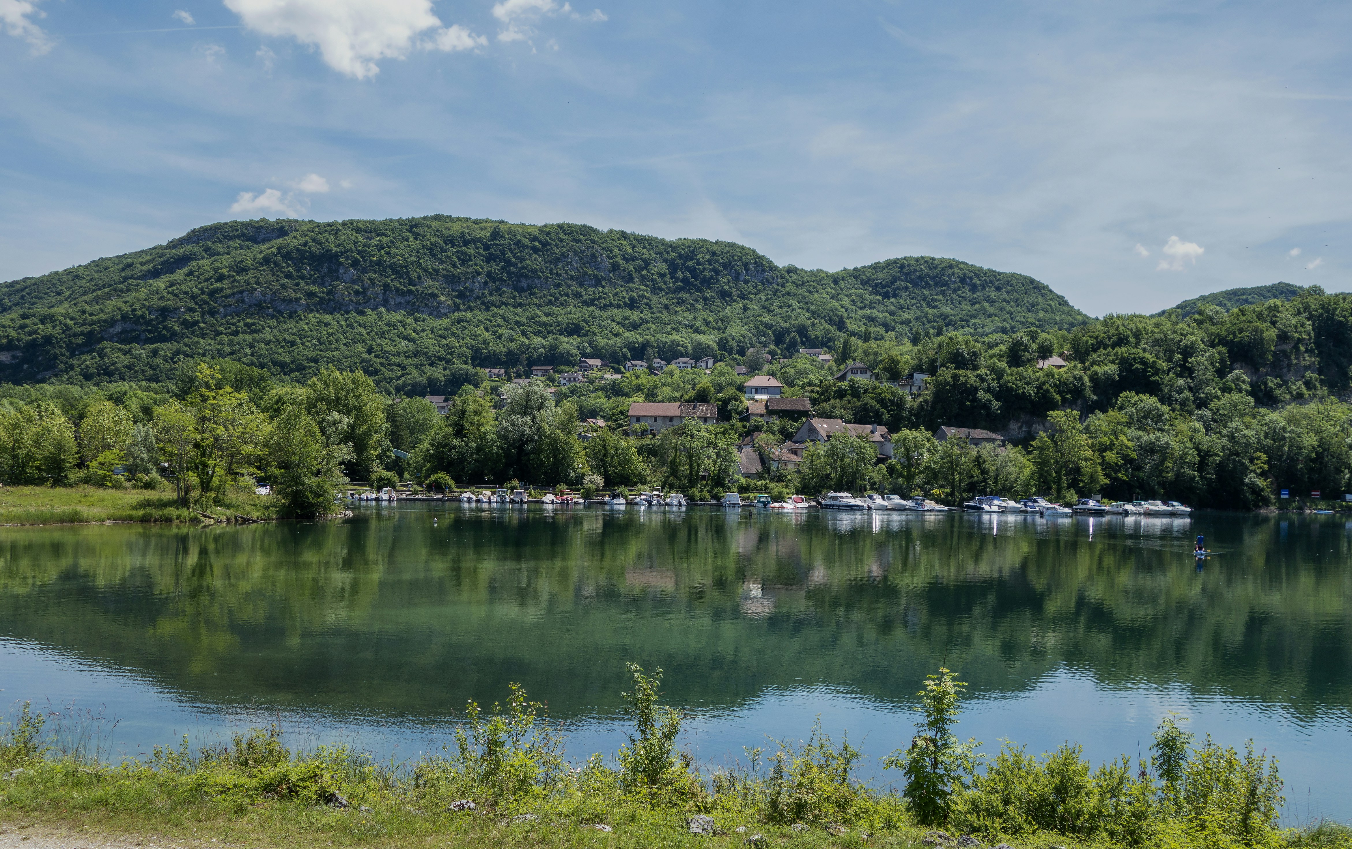 a body of water surrounded by a lush green hillside, Paysage le long du fleuve Rhône, de Genève à Lyon, avant d