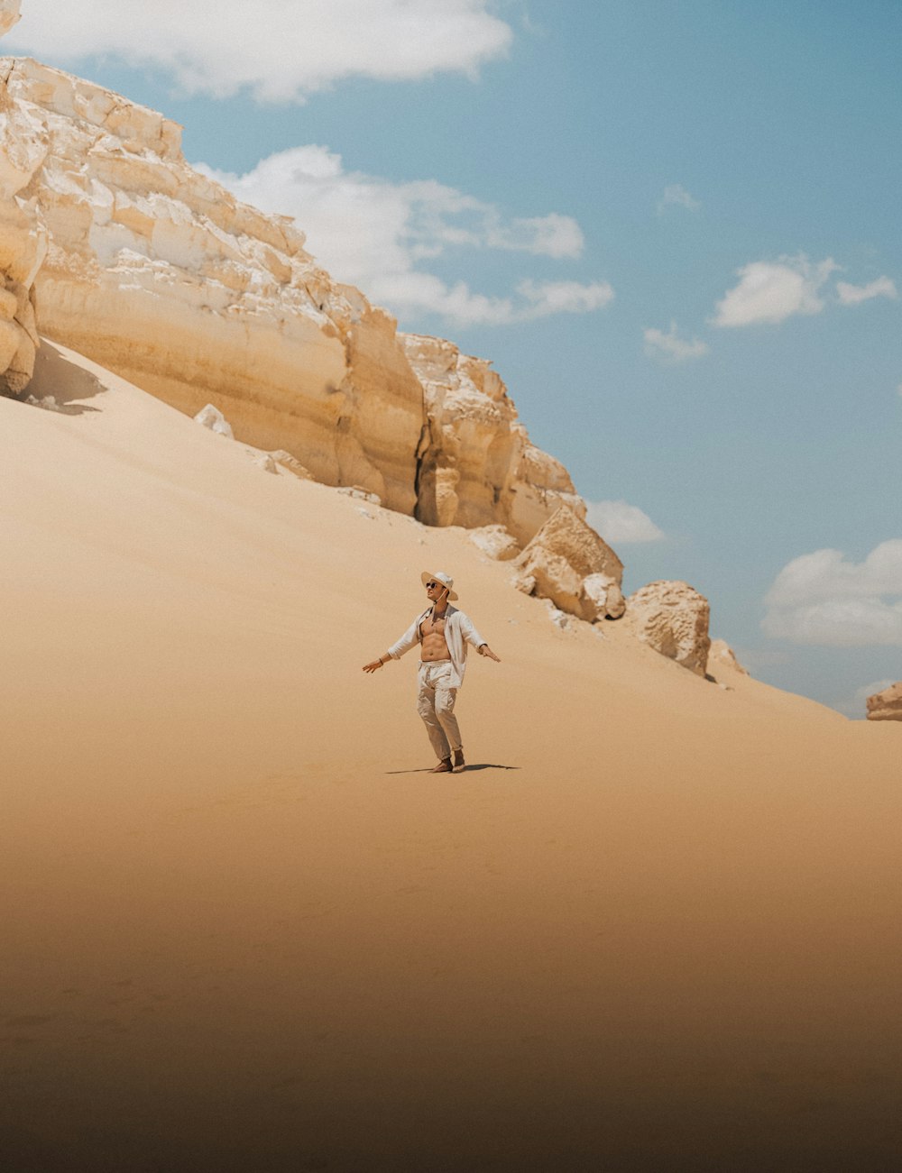 a man walking across a sandy desert under a blue sky