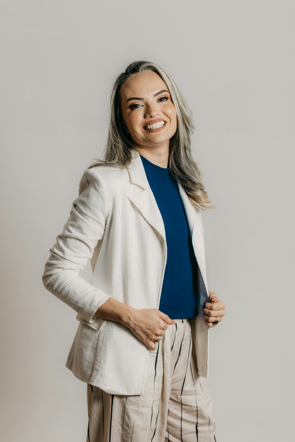 a smiling woman in a white jacket and striped pants