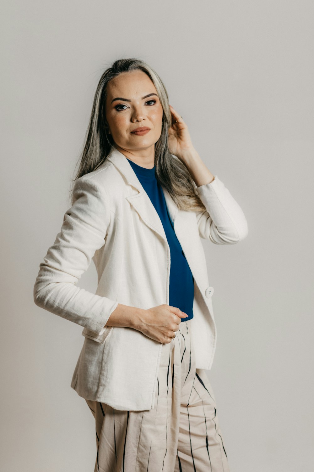 a woman in a white blazer is posing for a picture