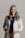 a smiling woman in a white jacket and brown pants