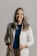 a smiling woman in a white jacket and brown pants