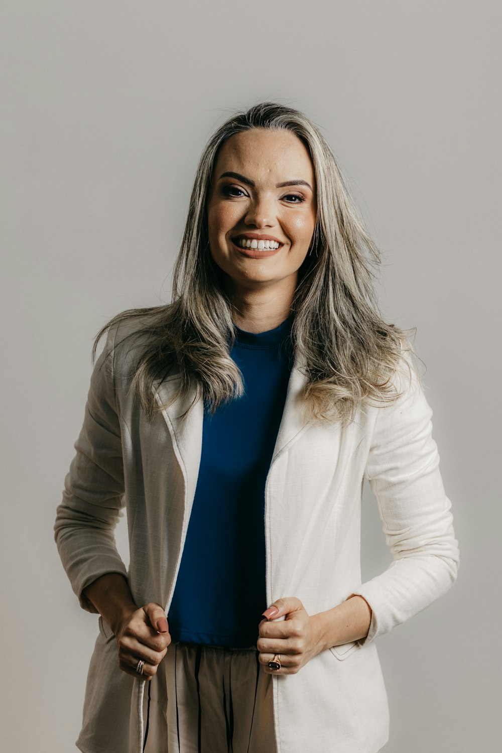 a smiling woman in a white jacket and brown pants