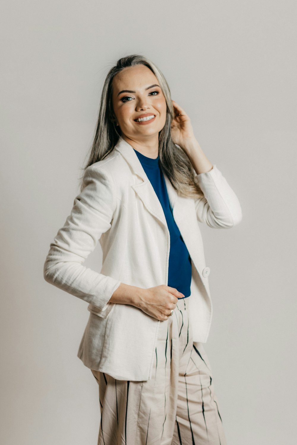 a woman in a white jacket and striped pants