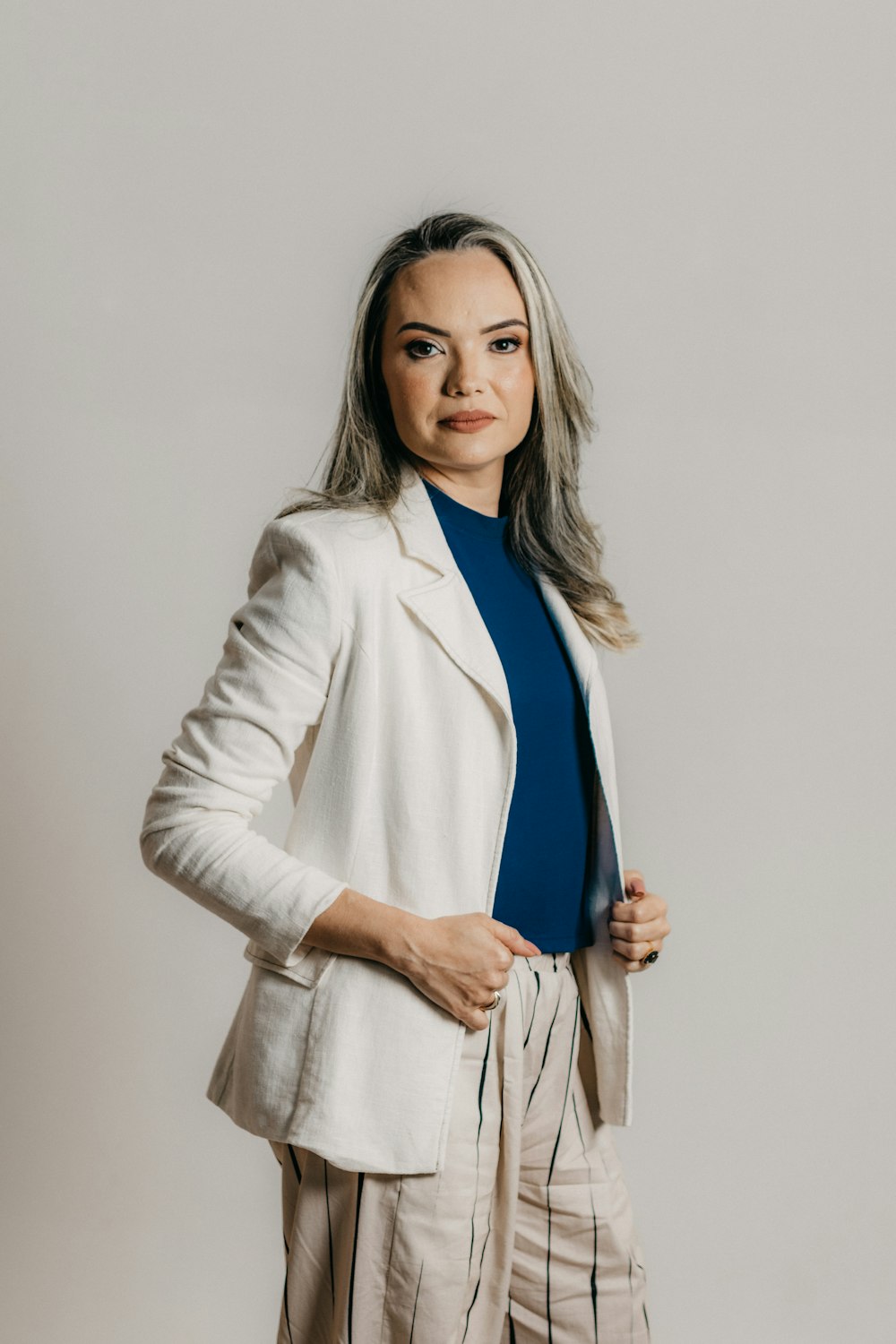 a woman in a white jacket and striped pants