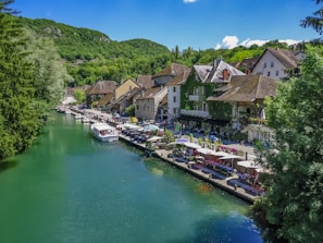 A cozy riverside village with boats docked and travelers relaxing nearby.