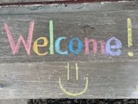 A smiling team member holding a welcome sign.