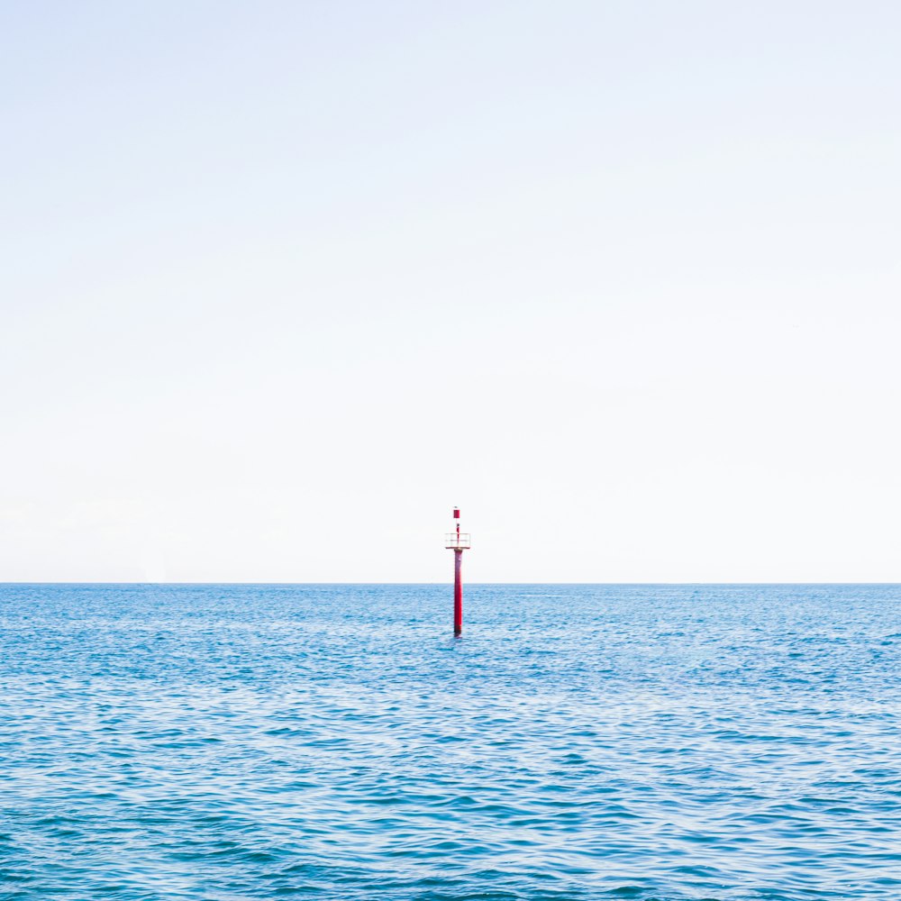 a red pole in the middle of a body of water