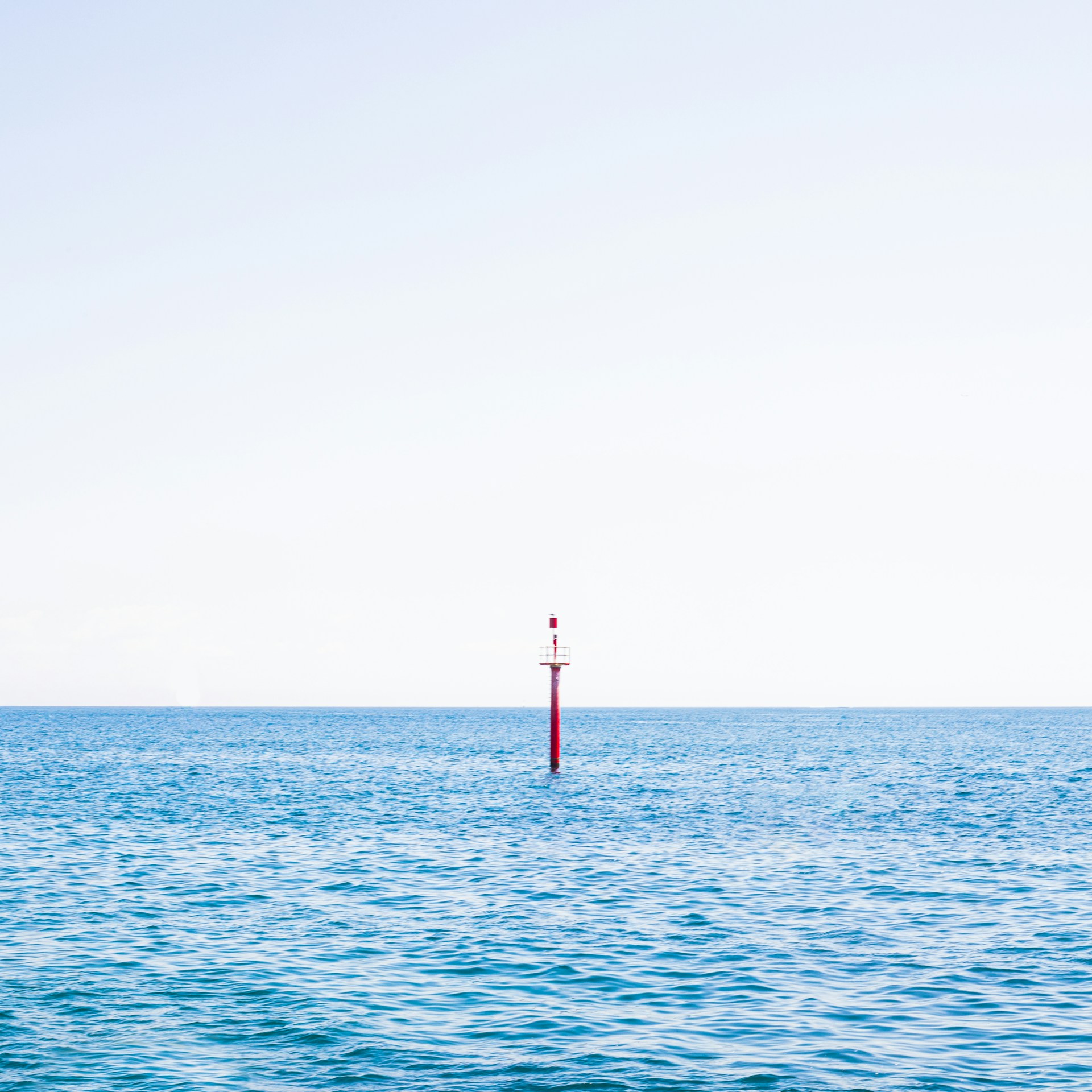 a red pole in the middle of a body of water