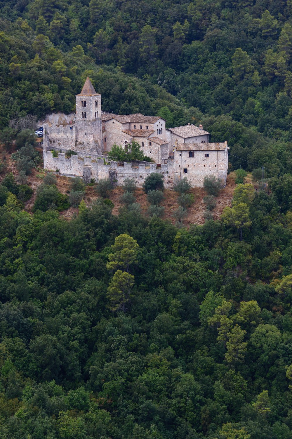 an old building on a hill surrounded by trees