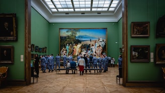 Group of artists gathered around a large canvas in a sunlit room.