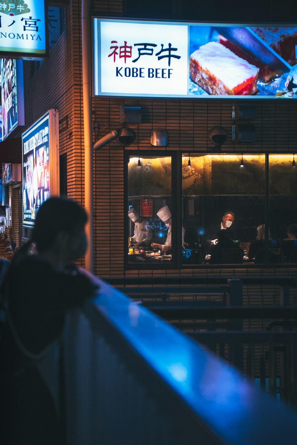 a person standing outside of a restaurant at night