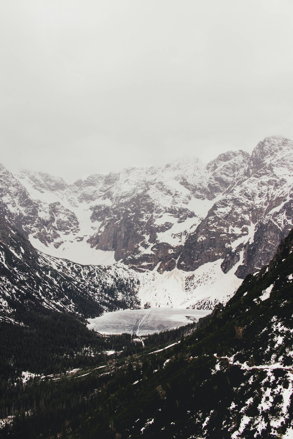 a snow covered mountain range with a lake in the middle