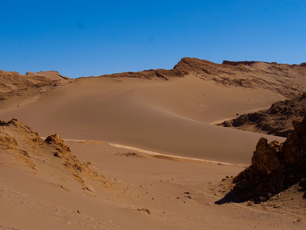 uma paisagem desértica com dunas de areia e um céu azul