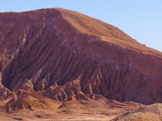 A terracotta red-hued mountain landscape under a clear sky, inviting adventure