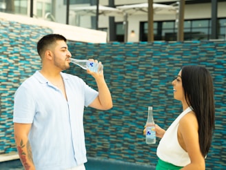 a man and a woman standing next to each other drinking water