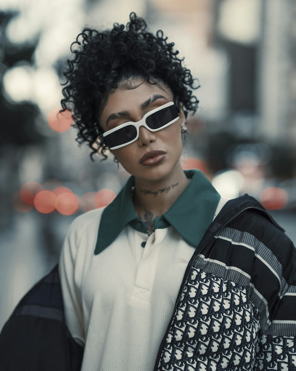 a woman with black curly hair and white sunglasses