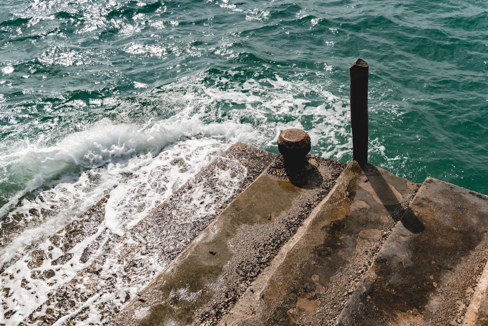 a pipe sticking out of the water next to a pier