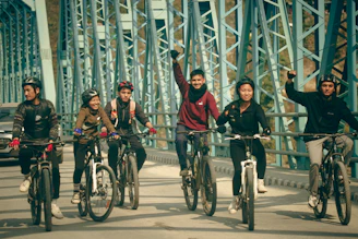 Group of riders crossing a rustic wooden bridge, smiles and determination on their faces.