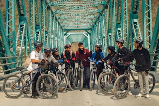 a group of people standing on a bridge with bikes